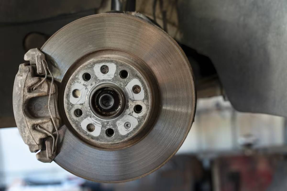 Close-up of a car brake disc and caliper, showing wear patterns and mounting details. An essential component of vehicle braking systems.