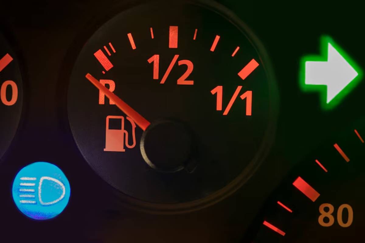 Close-up of a car dashboard showing fuel gauge slightly above empty, high beam indicator lit, and right turn signal light activated.