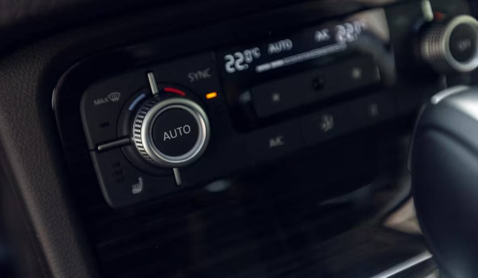 Close-up of a car's climate control panel showing the temperature set to 22°C, featuring auto and sync settings.