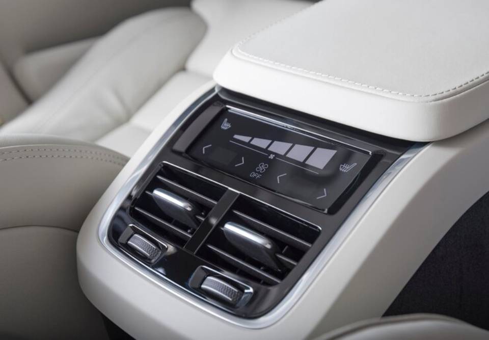 Close-up of a luxury car's climate control panel, featuring buttons for seat heating and air vents amidst a sleek, modern design.