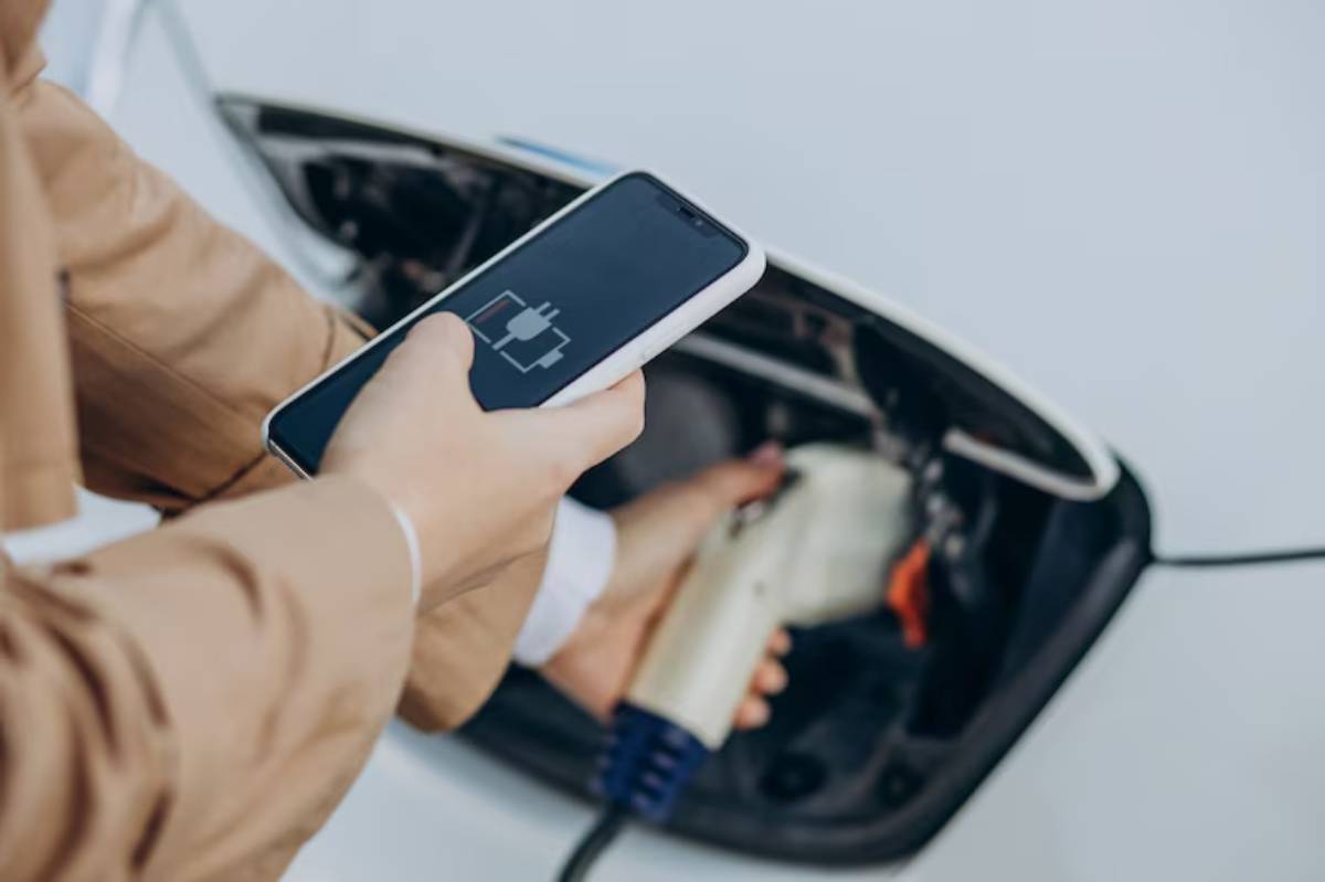 A person charges their electric car using a smartphone, demonstrating modern technology in sustainable transportation.