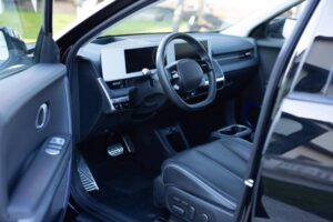 Interior view of a modern car showcasing a sleek dashboard, large display screens, and black leather seating.