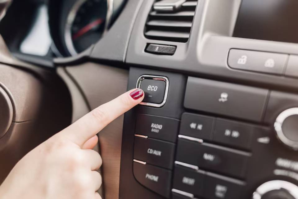 A woman is pressing a button on the car's radio, adjusting the volume or changing the station.