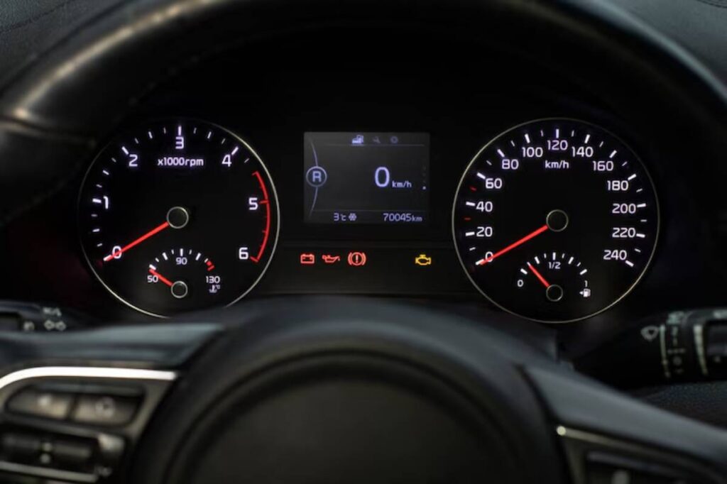 Dashboard view showing speedometer, tachometer, and digital display with mileage and warning lights illuminated.