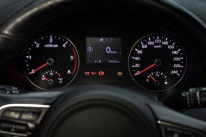 Dashboard view showing speedometer, tachometer, and digital display with mileage and warning lights illuminated.
