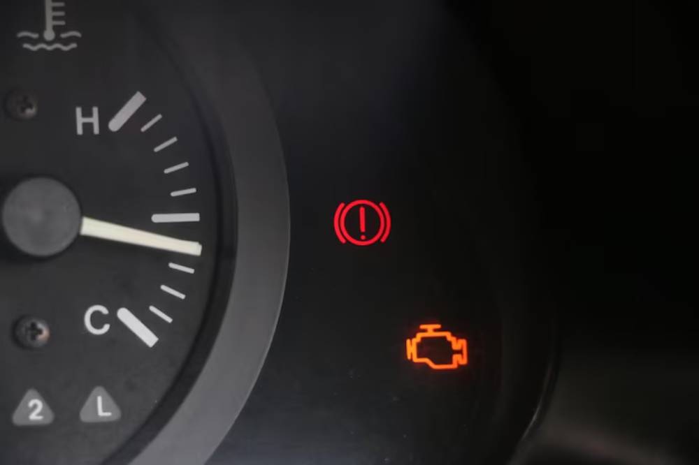 Dashboard warning lights displaying engine alert icon, general warning symbol, and temperature gauge indicating normal levels towards 'C'.