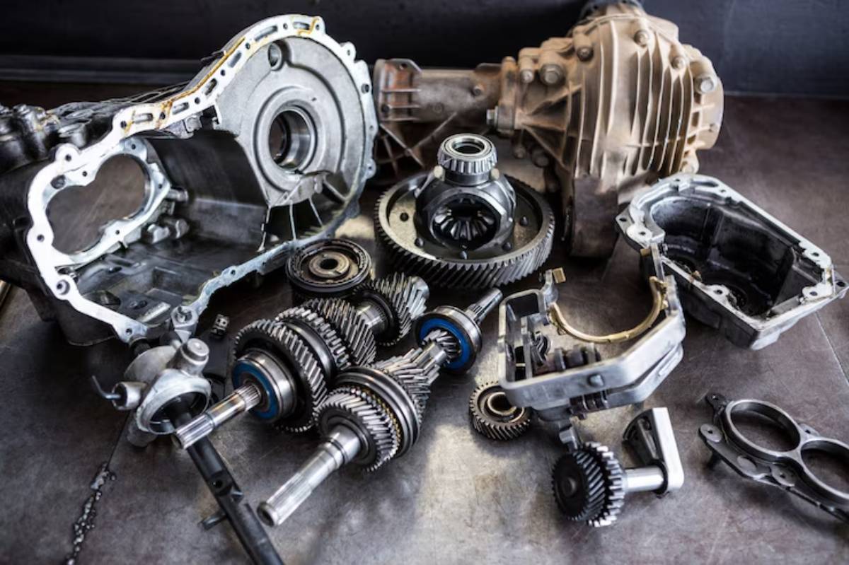 A collection of disassembled mechanical parts, including gears and casings, arranged on a dark surface.