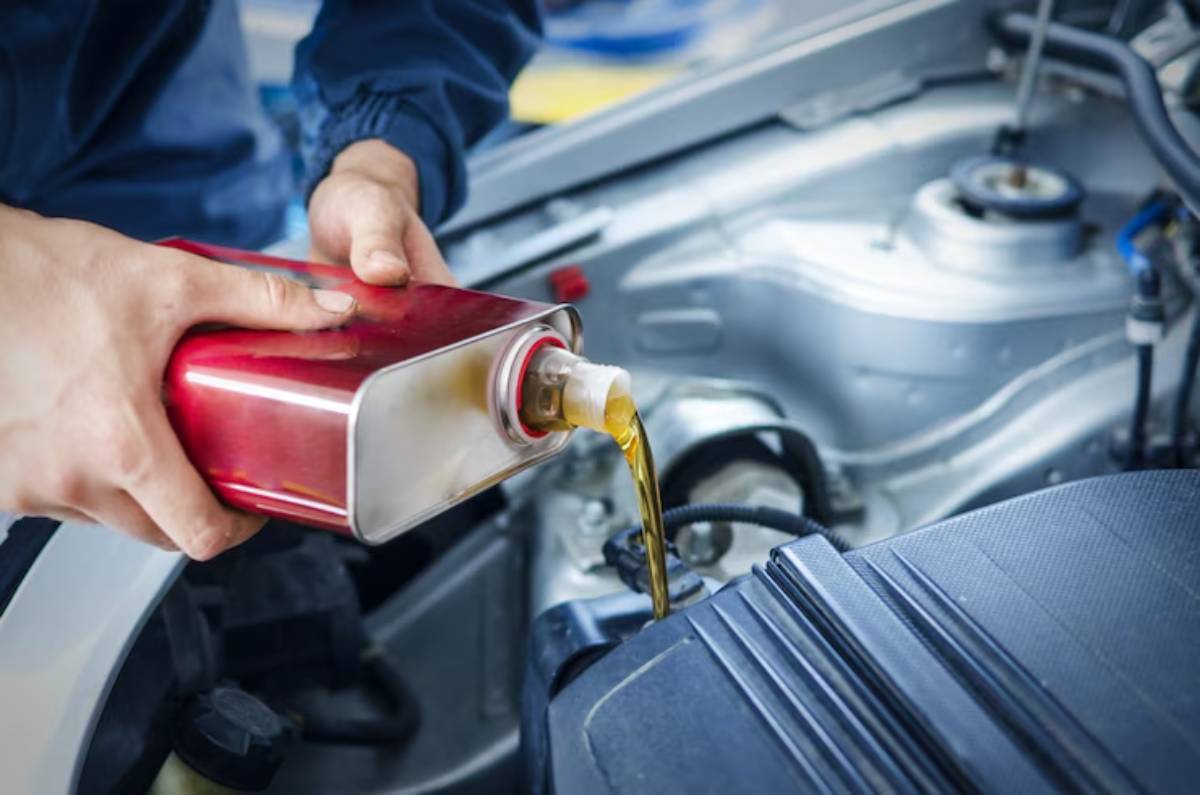 A person pours oil from a red canister into a car engine, highlighting vehicle maintenance and fluid replacement.